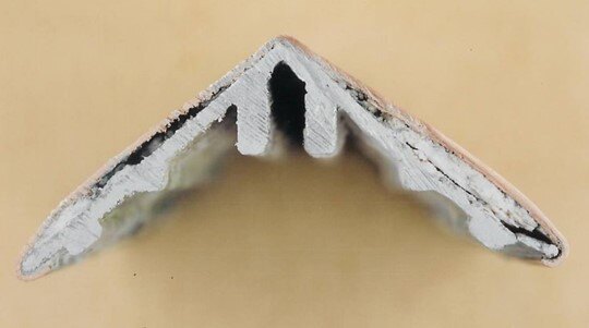 Cross-section of an aluminum dress cap clad with copper sheet showing white aluminum corrosion products