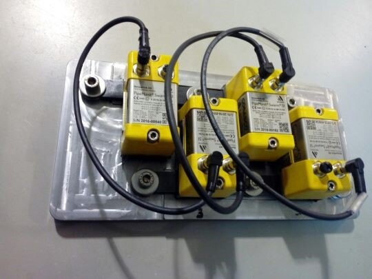 Steel test plate with four ultrasonic sensors positioned opposite the drilling location during the pitting detection experiment